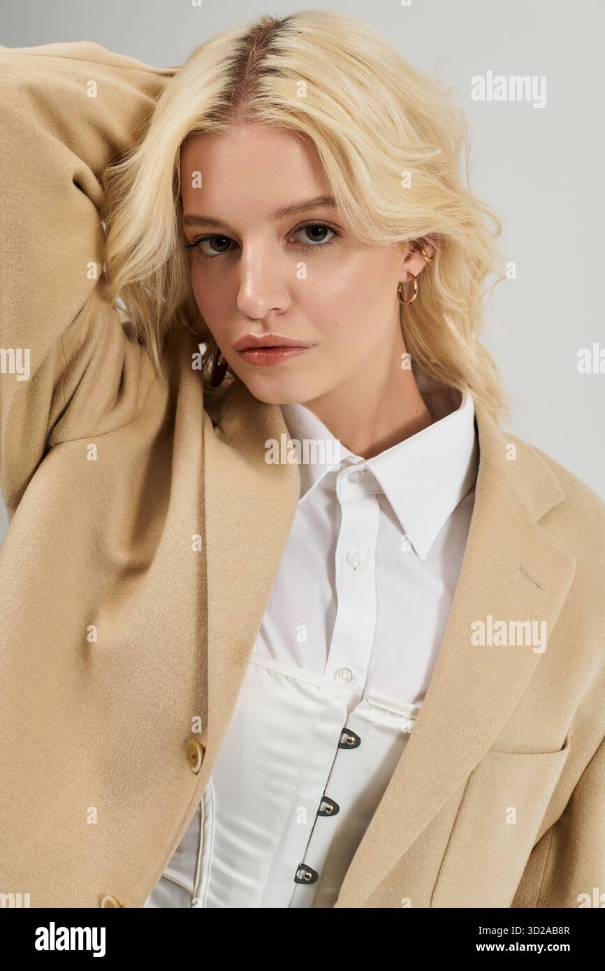 Die junge blonde Frau präsentiert ihr modisches Winteroutfit in einem hellen weißen Studio. Stockfoto