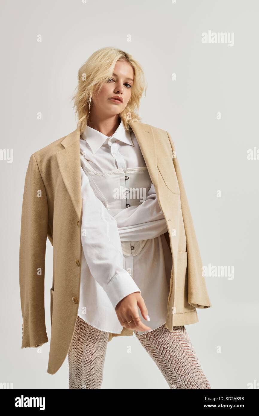 Eine schöne junge blonde Frau modelliert ein trendiges Winteroutfit in einem hellen, weißen Studio. Stockfoto