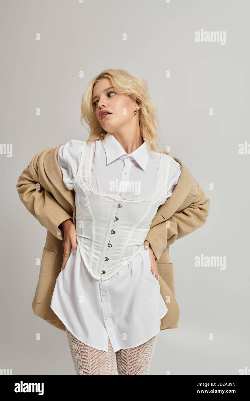 Eine schöne junge blonde Frau modelliert ein trendiges Winteroutfit in einer hellen weißen Studioatmosphäre. Stockfoto