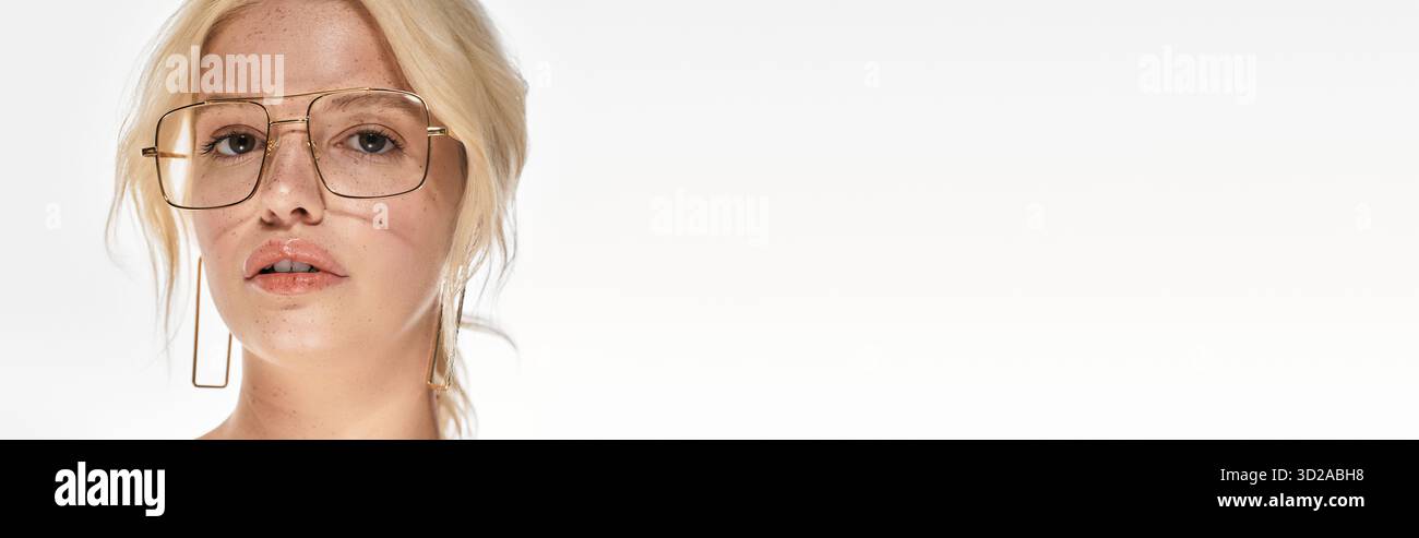 Die junge blonde Frau zeigt trendige Winterkleidung in einem stilvollen weißen Studio, Banner Stockfoto