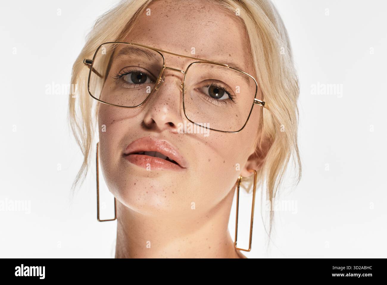 Eine schöne junge blonde Frau posiert selbstbewusst in einem weißen Atelier Stockfoto