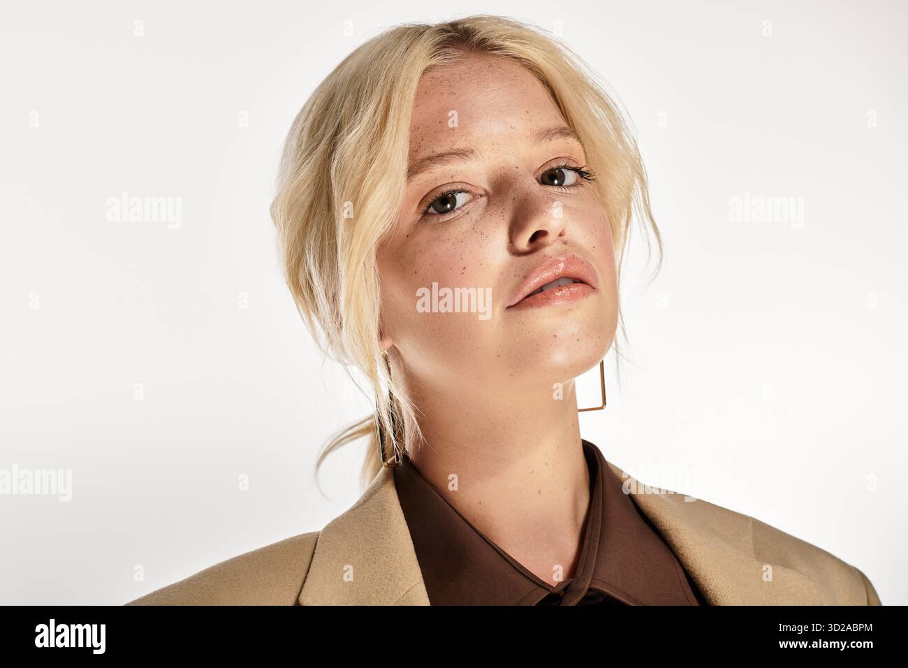 Stilvolle junge Frau posiert selbstbewusst in einem hellen, weißen Studio-Raum in Winterkleidung. Stockfoto