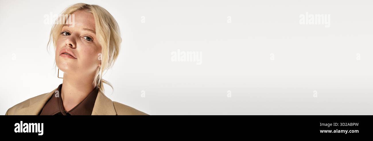 Eine stilvolle junge blonde Frau posiert elegant in einem weißen Studio und hebt Wintermodetrends und Banner hervor Stockfoto