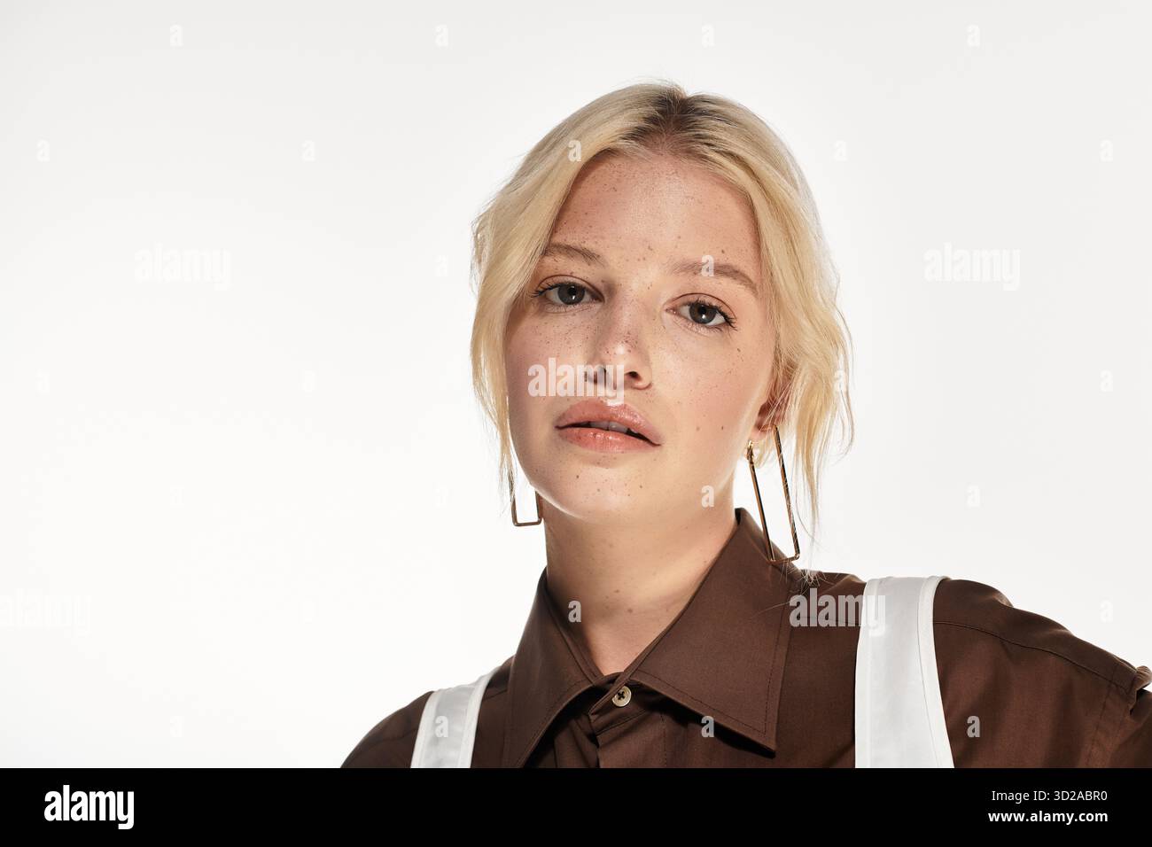 Stilvolle junge Frau posiert selbstbewusst in einem weißen Studio und hebt ihre Winterkleidung hervor. Stockfoto