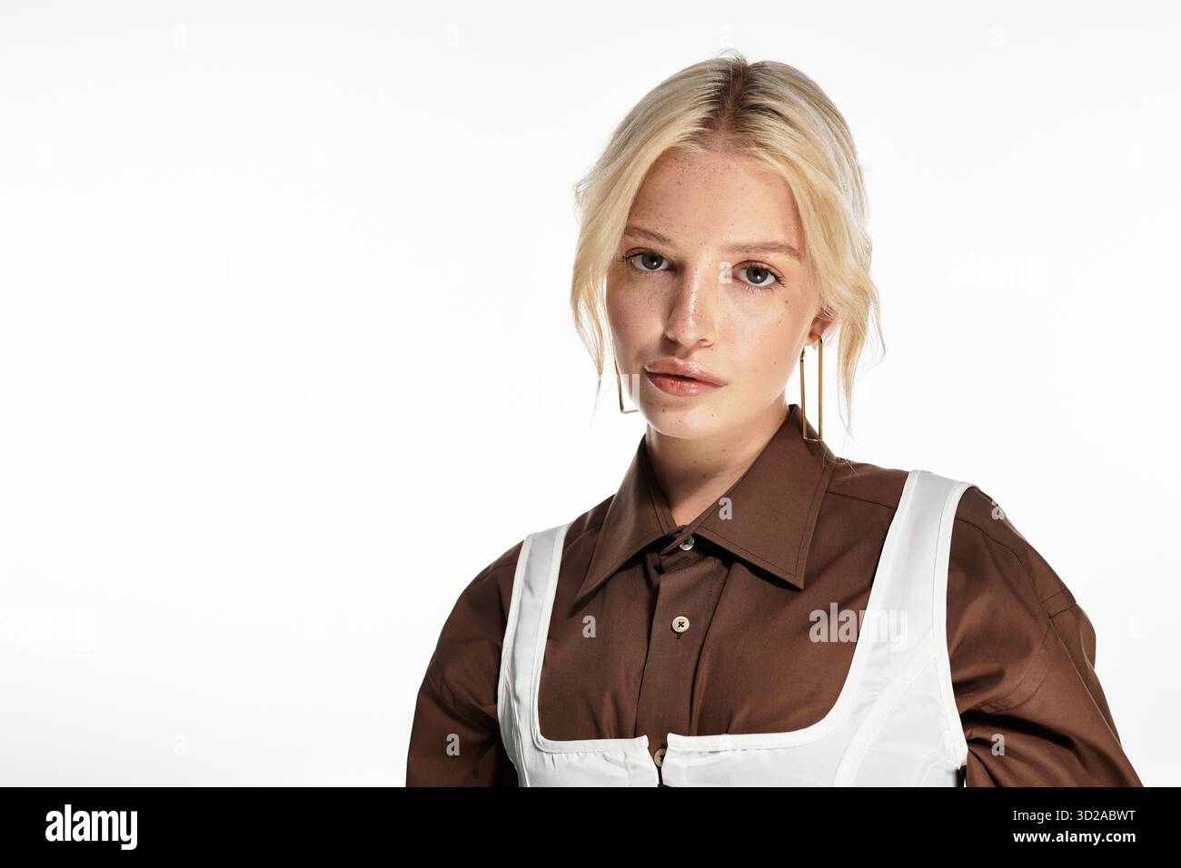Eine junge blonde Frau im trendigen Winteroutfit glänzt in einem weißen Studio. Stockfoto