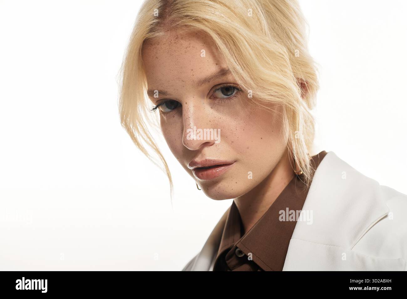 Eine schöne junge blonde Frau posiert selbstbewusst in einem weißen Studio und zeigt Wintermode. Stockfoto