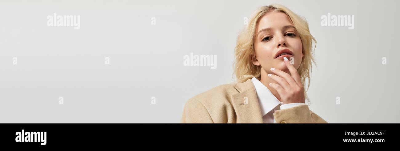 Eine schöne junge blonde Frau zeigt Wintermodetrends in einem eleganten weißen Studio, Banner Stockfoto