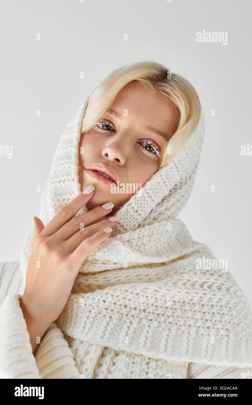 Eine junge Frau mit weißen Wimpern trägt einen warmen Strickpullover, der eine einladende Atmosphäre schafft. Stockfoto