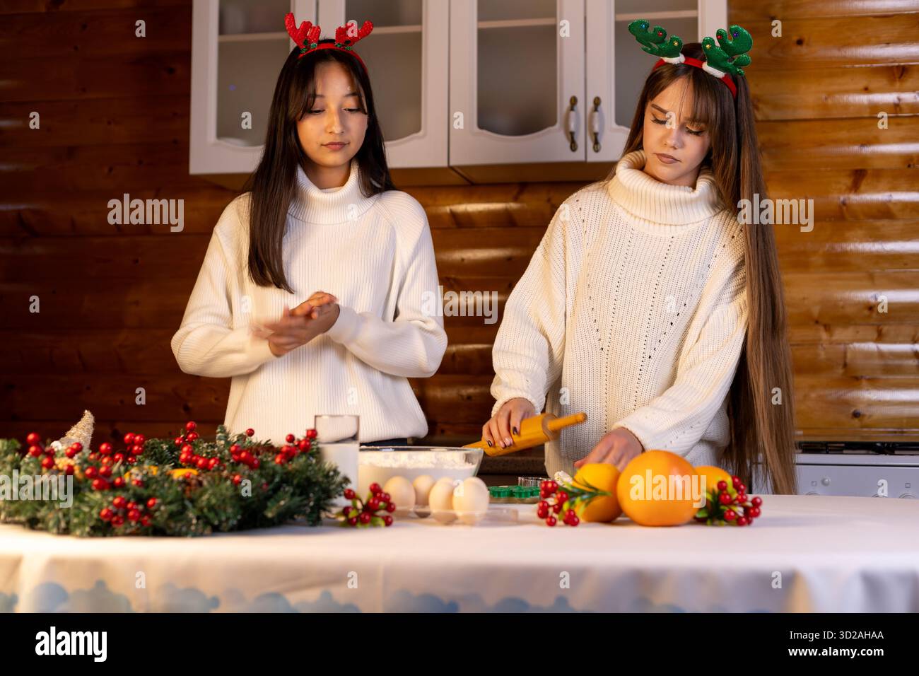 Zwei Mädchen bereiten Weihnachtsdekorationen und Essen in festlicher Umgebung vor Stockfoto
