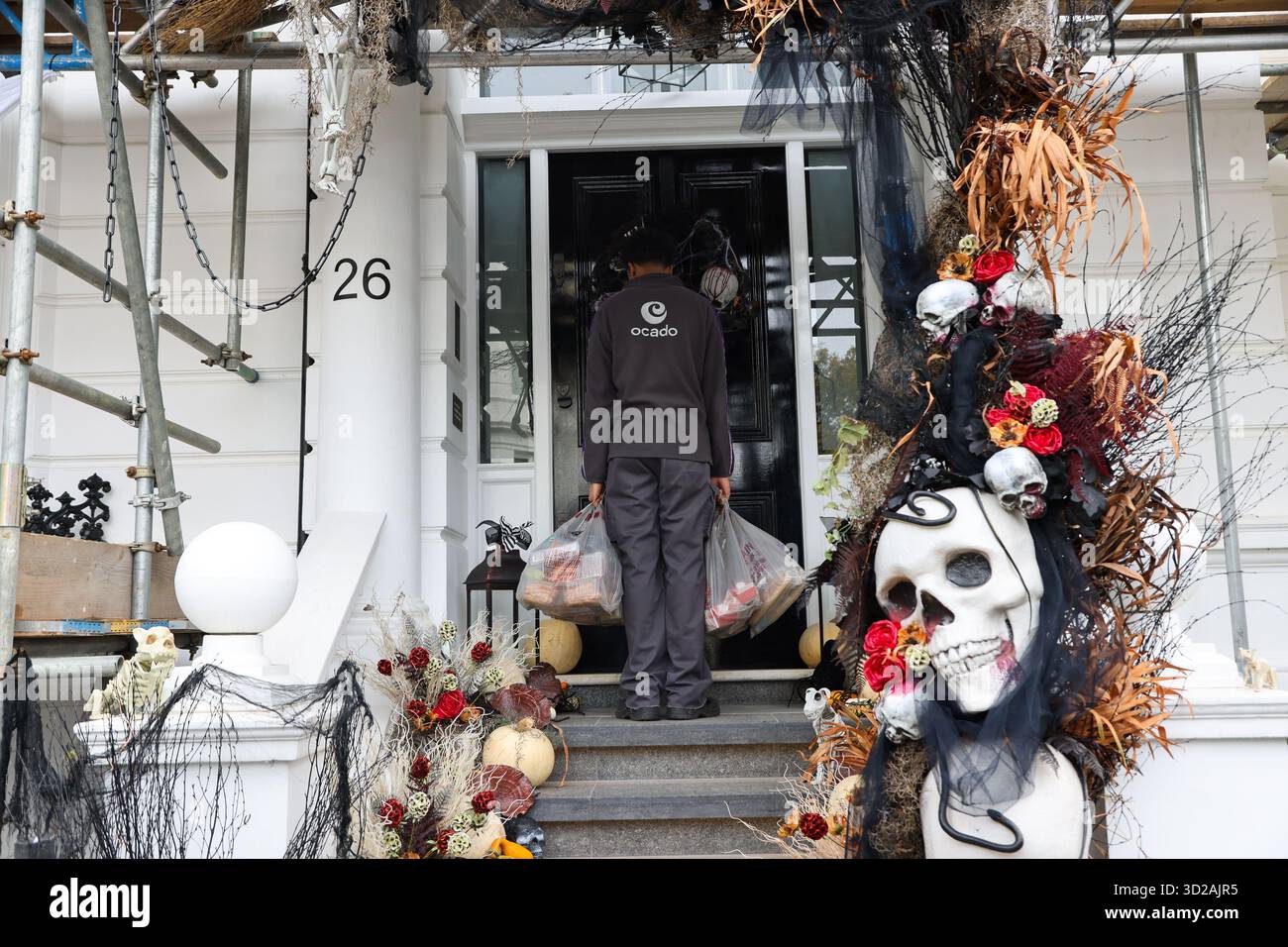 London, Großbritannien. 30. Oktober 2025. Ein Ocado-Liefermann liefert zu einer Halloween-Ausstellung vor einem Wohnhaus in Kensington, West-London, vor den Feierlichkeiten. Quelle: SOPA Images Limited/Alamy Live News Stockfoto