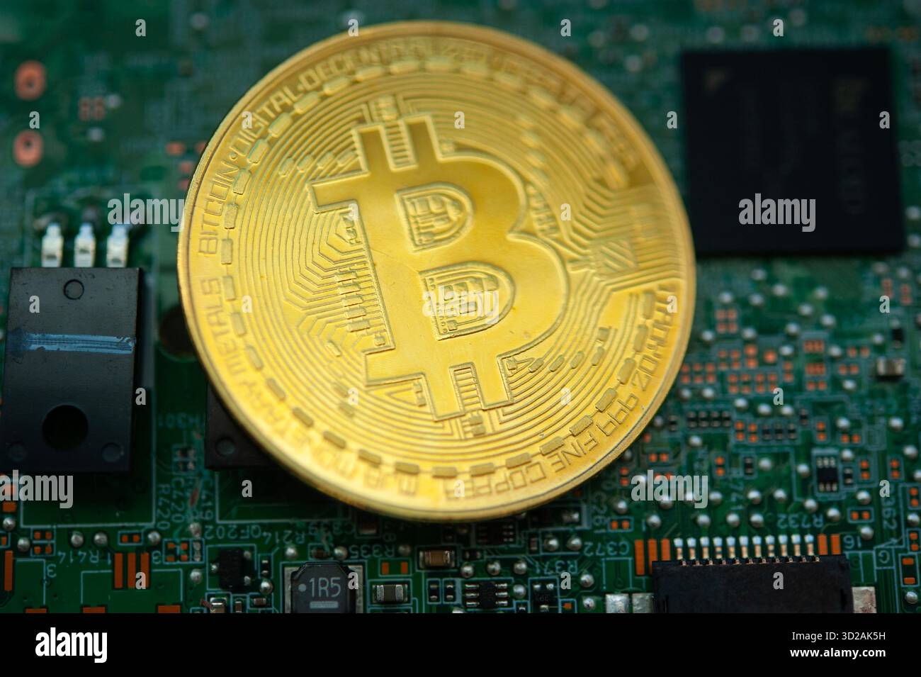 Physische Bitcoin-Münze auf Computermotherboard, die Kryptowährungs-Mining und Blockchain-Technologie repräsentieren Stockfoto
