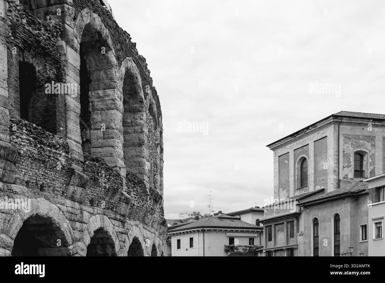Der Blick auf die Arena von Verona zeigt das römische Mauerwerk und die mehrschichtigen Bögen aus Stein und Ziegeln, die im Kontrast zu den nahe gelegenen Wohngebäuden aus dem späteren Jahrhundert stehen Stockfoto