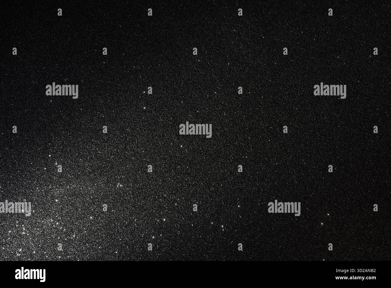 Dunkler körniger Hintergrund mit asphaltartigem Relief und verstreuten Funkeln, beleuchtet von unten links, wodurch eine stimmungsvolle abstrakte Szene mit scharfer Textur entsteht Stockfoto