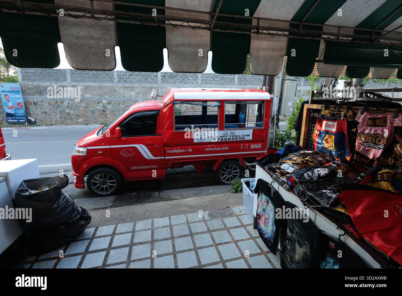 Kleiner roter asiatischer Minibus vor einem Markt mit Leinwandmarkise in Thailand - keine Leute Stockfoto