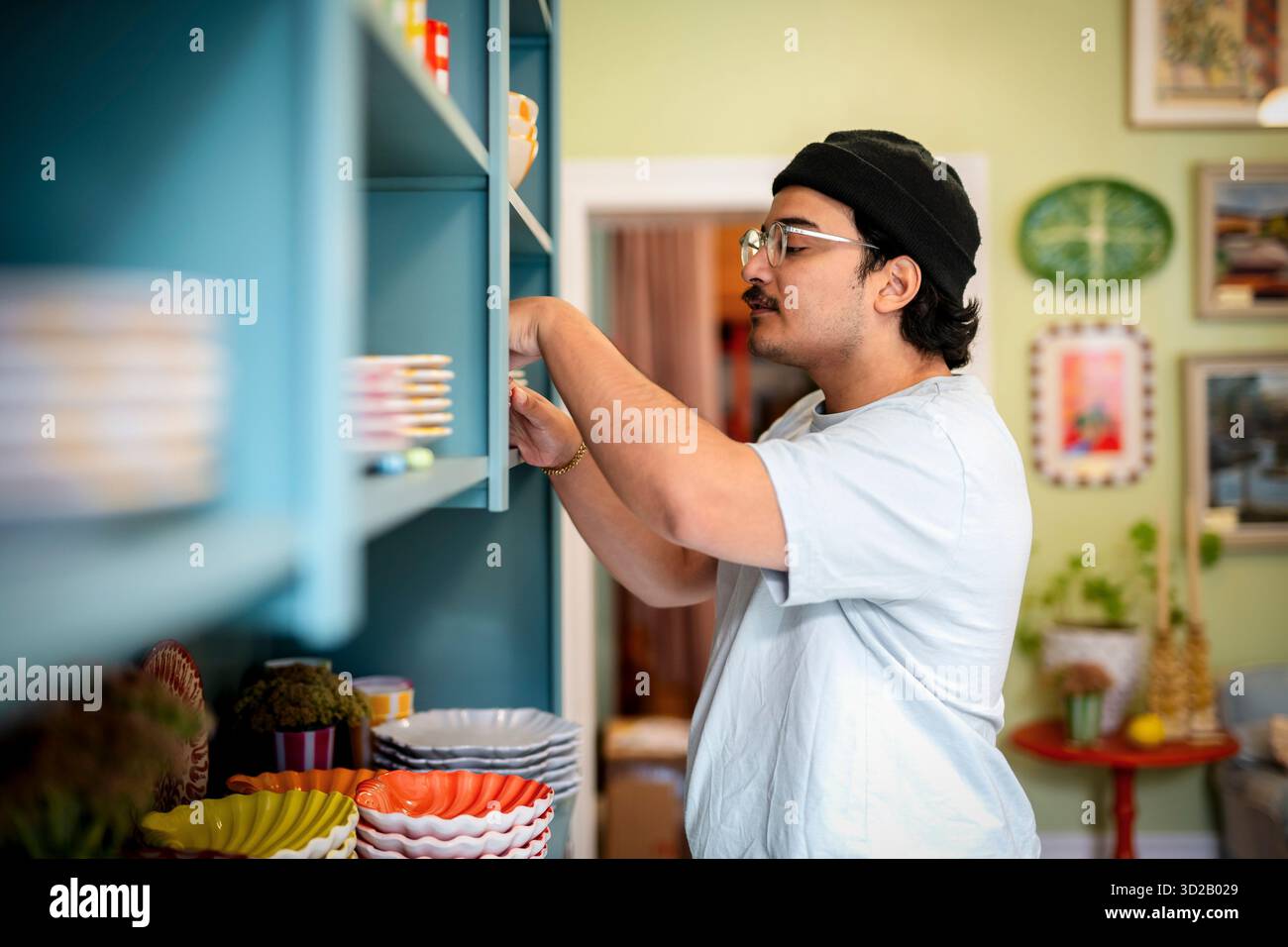 Seitenansicht des Verkäufers, der die Teller auf einem Regal im Innenausstatter anordnet Stockfoto