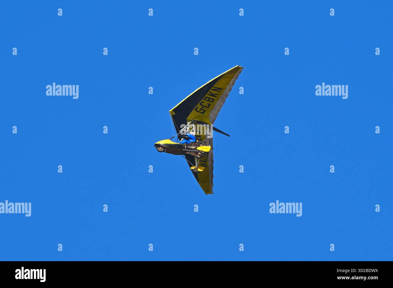 Ein gelbes Mikrolicht-Flugzeug G-CBKN im Flug gegen einen blauen Himmel. UK Stockfoto