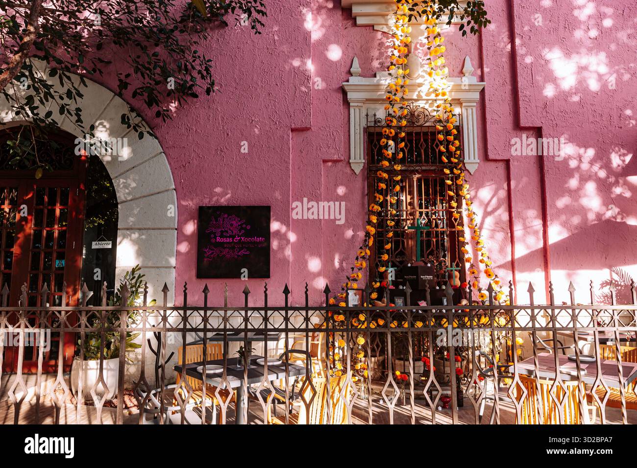 Merida, Yucatan, Mexiko, rosafarbenes Gebäude mit einem großen Bogengang und einem Schild mit der Aufschrift „La Casa de la Flor“. Stockfoto