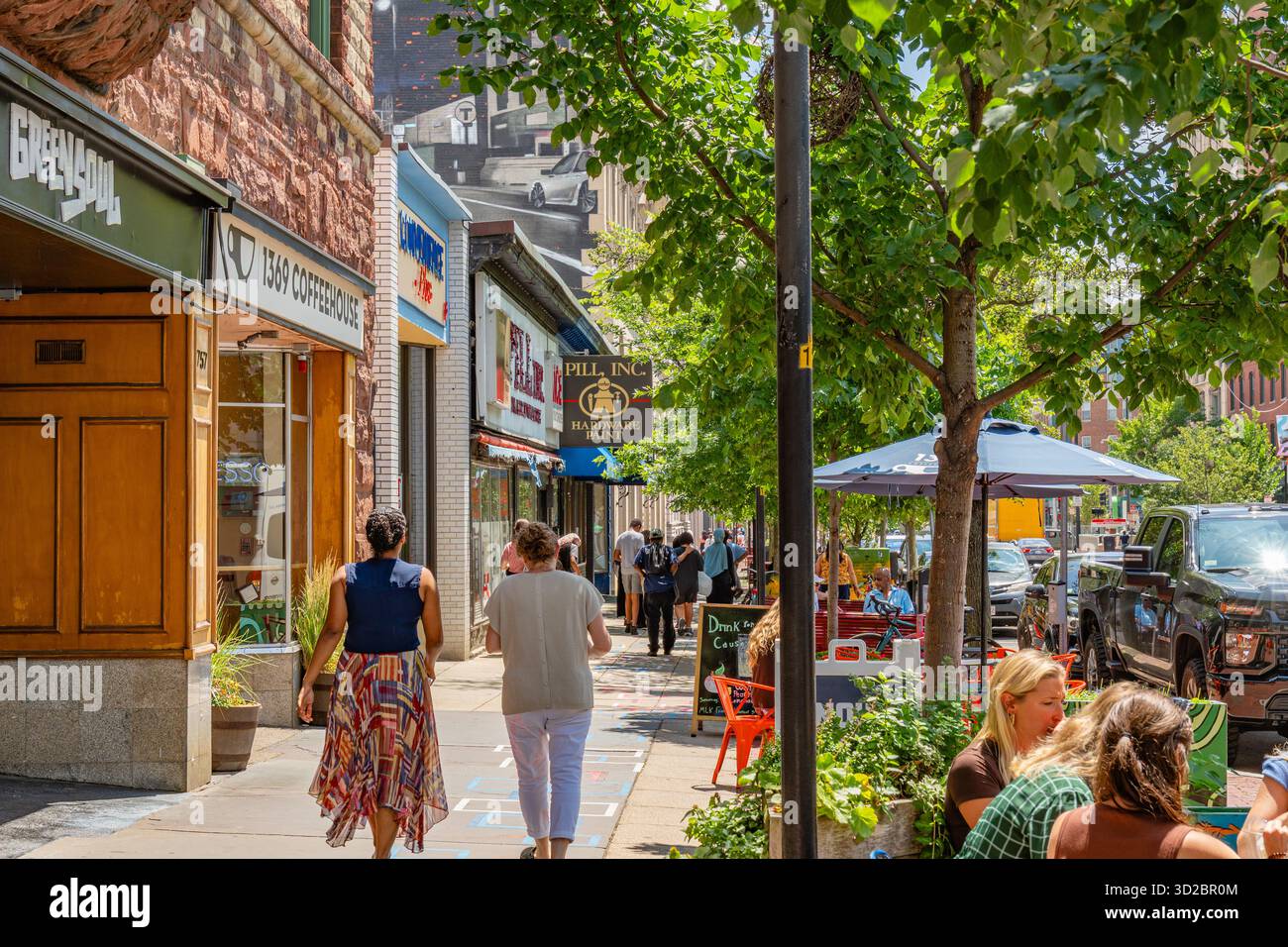 Cambridge, MA, USA-15. Juli 2025: Fußgänger spazieren an einem sonnigen Sommertag auf einem belebten Bürgersteig Harvard Square. Stockfoto