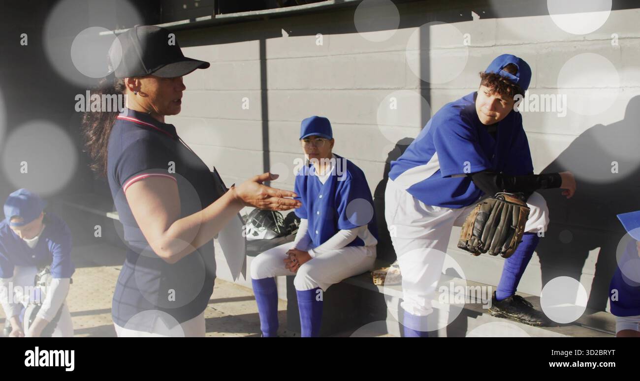 Gestentrainer, der vier Spieler im Baseballdugout anspricht, mit Handschuhen und Helmen, Kopierraum Stockfoto