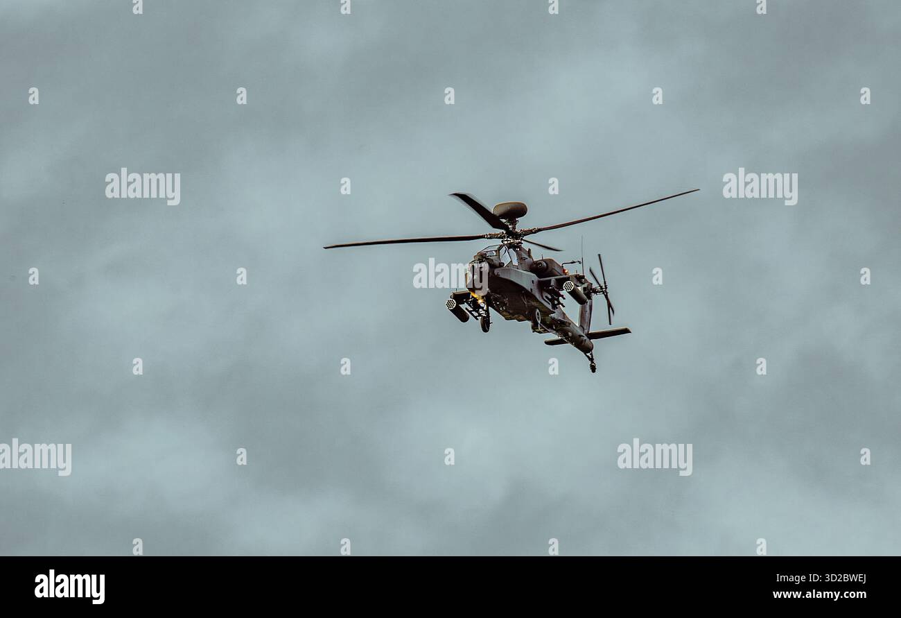 Militärischer Angriff Apache Helikopter, der bei bewölktem Himmel während einer Überwachungs- oder Kampfmission mit sichtbarer Ausrüstung und Waffen fliegt Stockfoto