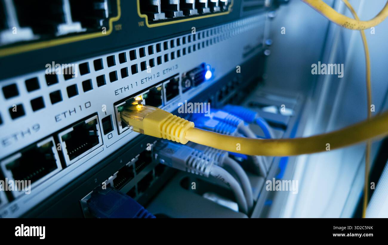 Netzwerk-Switch mit gelbem ethernet-Kabel, das an den Port angeschlossen ist, zeigt moderne Dateninfrastruktur, Hochgeschwindigkeitsverbindung und IT-Systeme Stockfoto