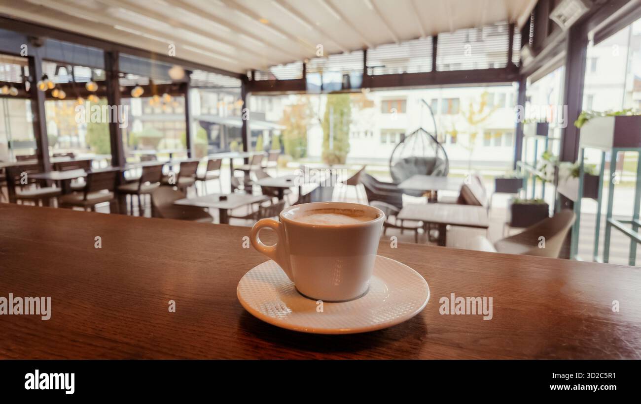 Tasse Kaffee auf Holztheke im modernen Café mit heller Inneneinrichtung, natürlichem Licht und gemütlicher Atmosphäre, perfekt für Lifestyle oder Gastfreundschaft Stockfoto