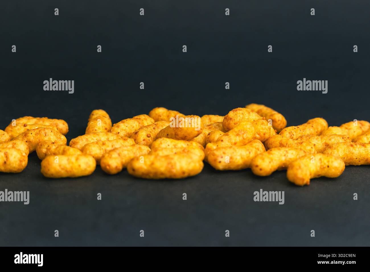 Knusprige Erdnusspuff-Snacks auf dunklem Hintergrund, knusprige, salzige Bissen perfekt für Fast-Food-Werbung, Verpackung und Snack-Produktdesign Stockfoto