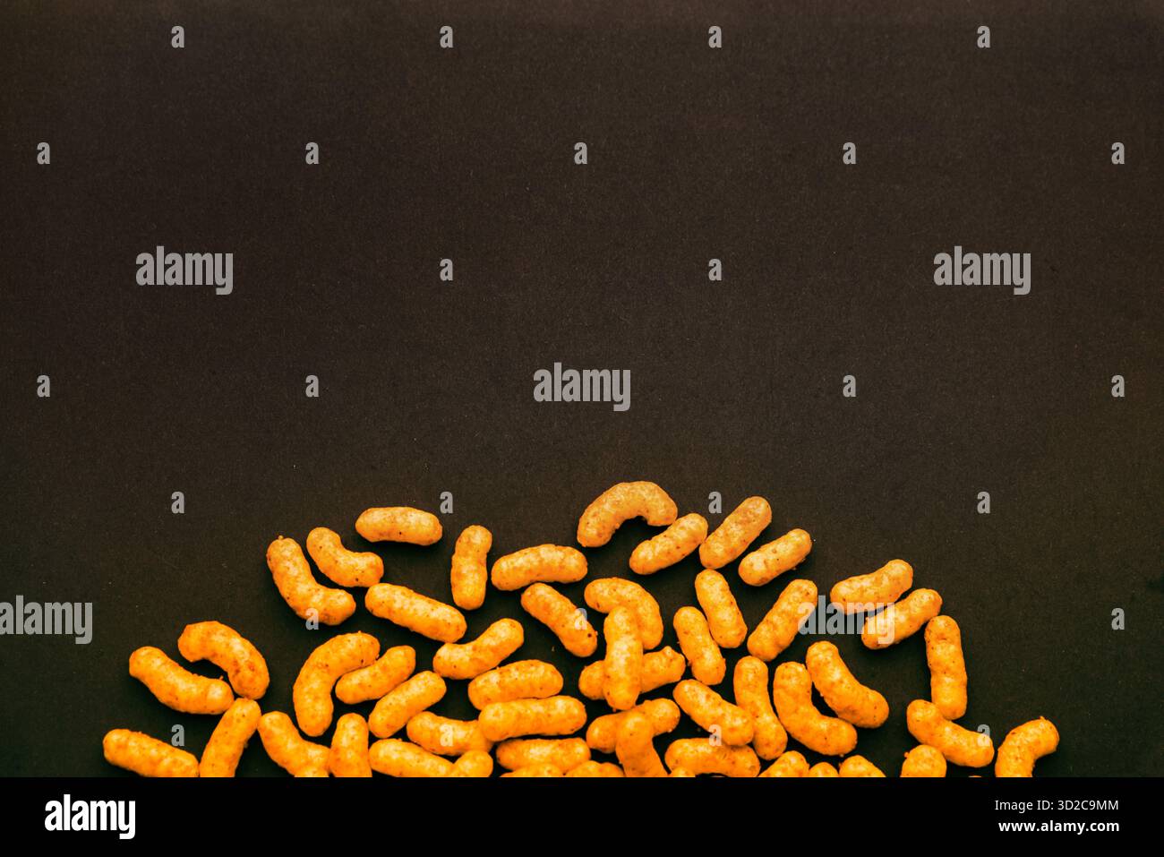 Erdnusspuffer-Snacks auf dunkler Oberfläche mit leerem Kopierraum, minimalistischer Lebensmittelhintergrund perfekt für Banner- oder Verpackungsmockup Stockfoto