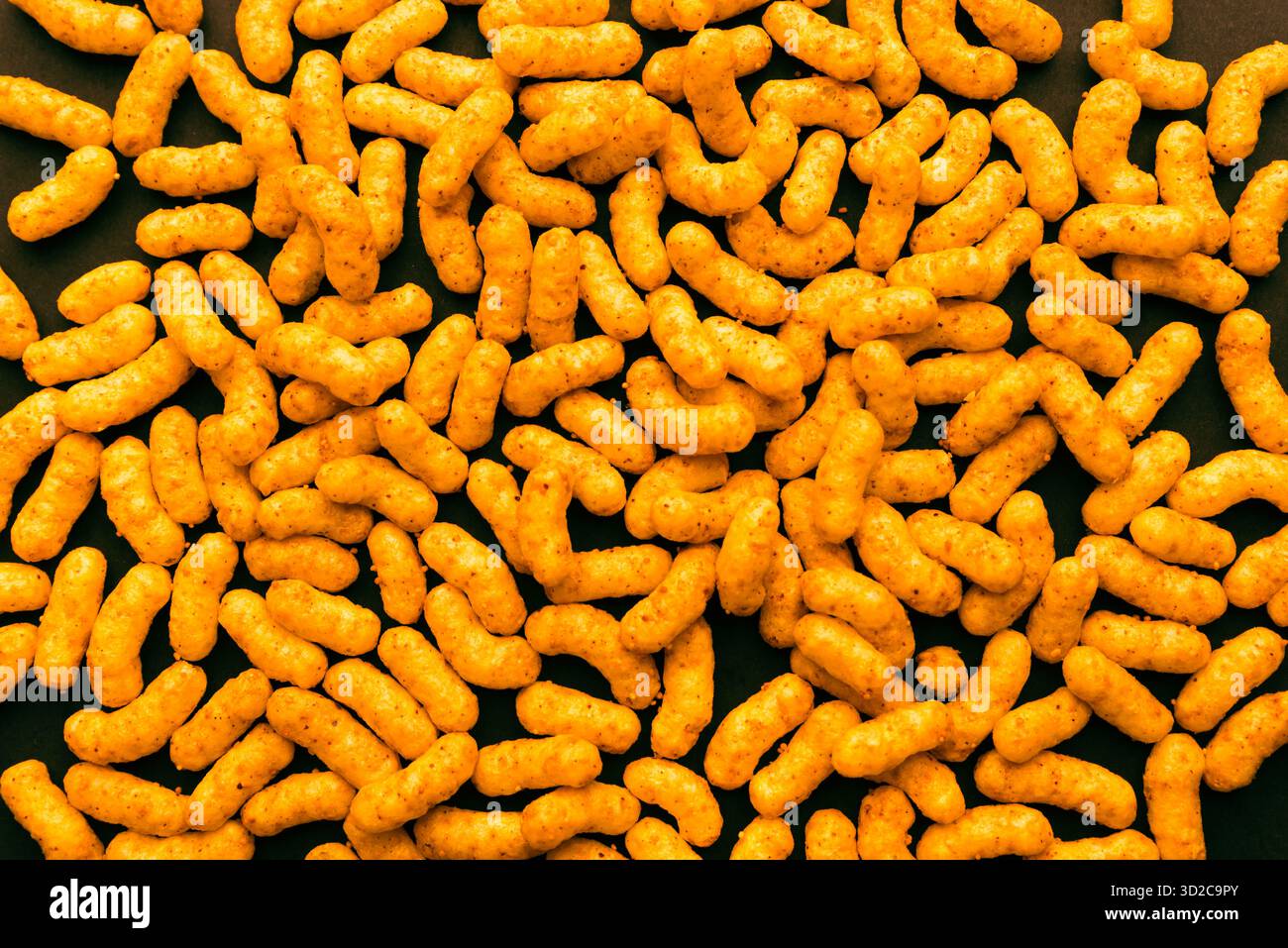 Goldene Erdnuss-Blätterteig-Snacks, dicht auf dunklem Hintergrund angeordnet, knusprige salzige Textur für Lebensmittelverpackungen, kommerzielles Design oder Snack-Branding Stockfoto