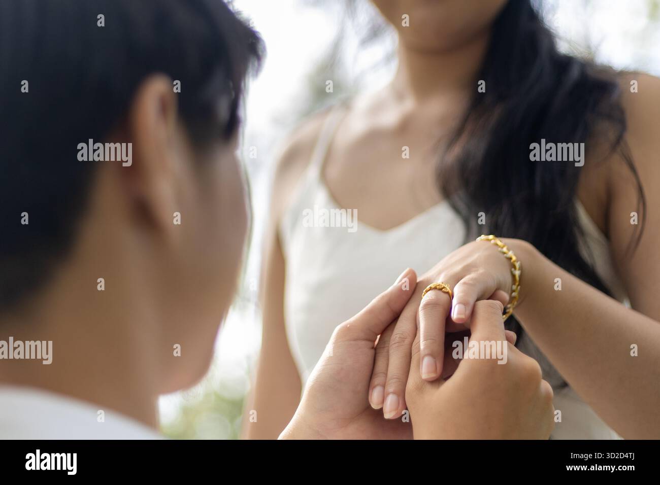 Selektiver Diamant-Ring aus Gold an der Hand der jungen Frau Er hält die Hand einer jungen Frau, nachdem er einen Ring aufgelegt und ihr einen Antrag gemacht hat. Stockfoto