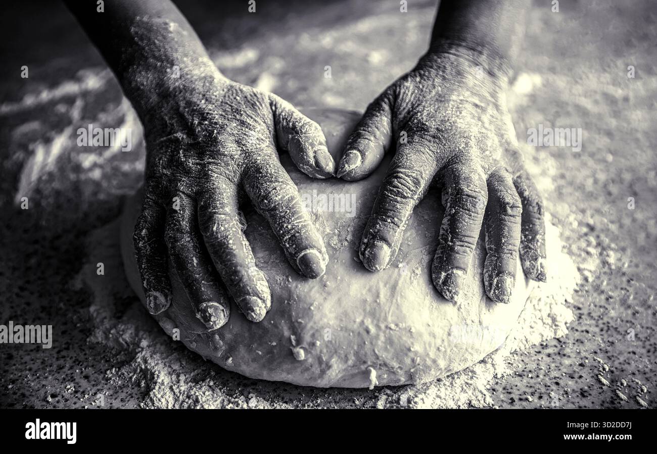 Lebensmittelkonzept. Hände Teig. Weibliche Hände machen Teig für Pizza. Der Koch in der professionellen Küche bereitet den Teig zu. Schwarz-weiß Stockfoto