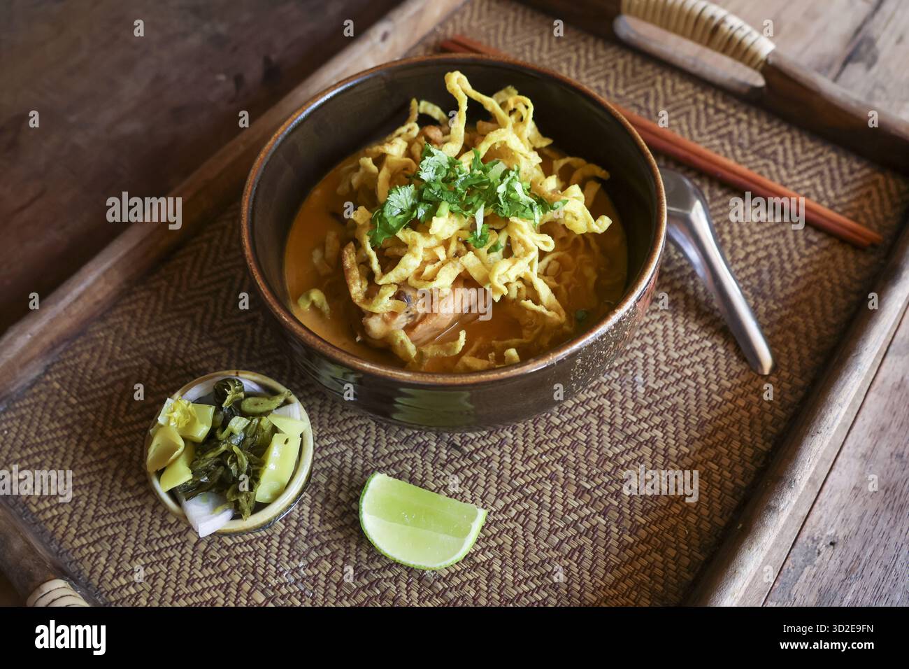 Köstliches Khao Soi, herzhaftes thailändisches Essen mit Noodle Curry Suppe. Diese traditionelle asiatische Küche in einer Schüssel mit Limette und Gurke bietet einen Appet Stockfoto