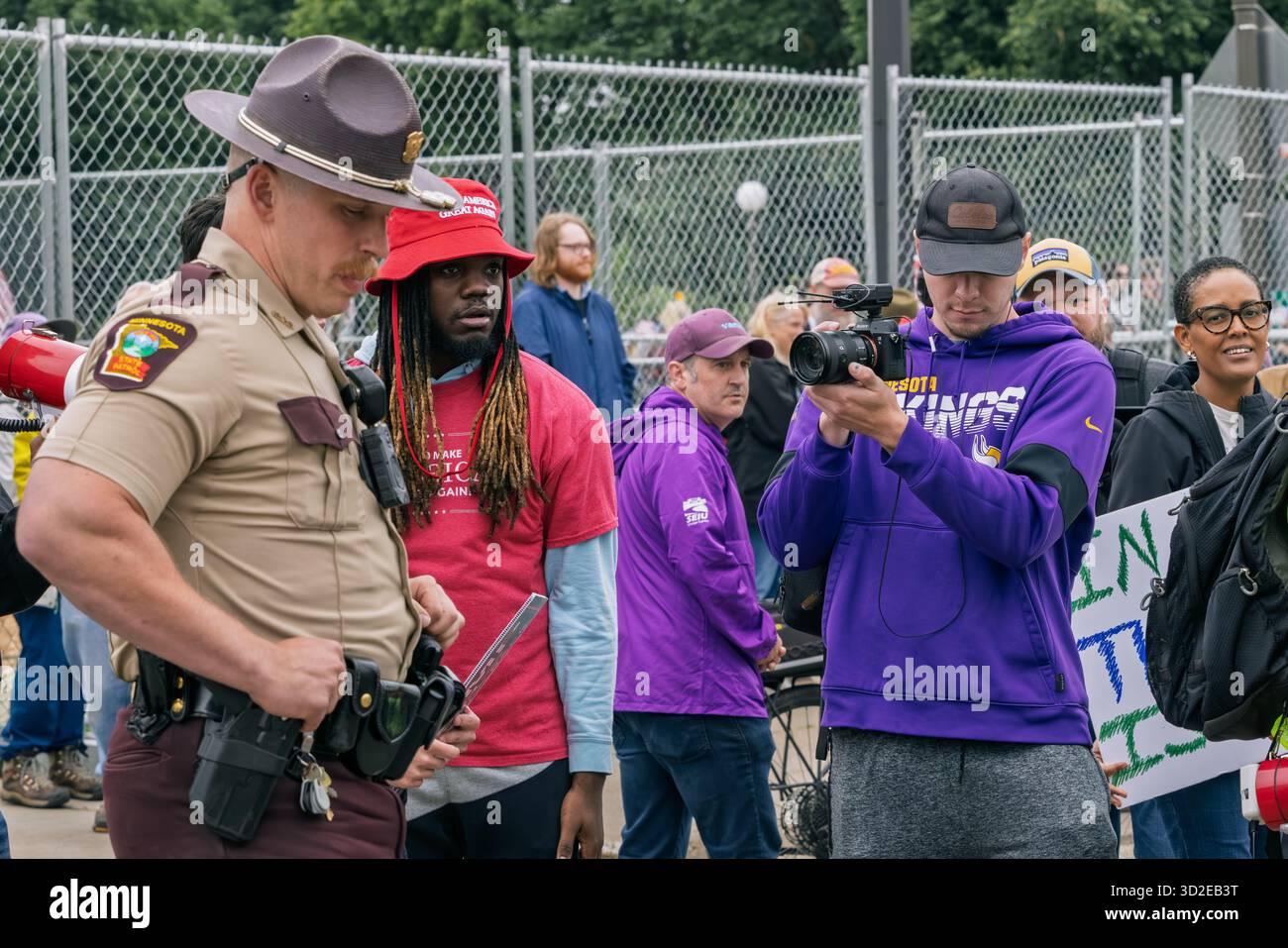 Der staatliche Trooper verwaltet die Massenkontrolle zwischen selbstfilmenden MAGA-Anhängern und Anti-Trump-Demonstranten bei der No Kings Demonstration, St. Paul, USA, Juni 2025 Stockfoto