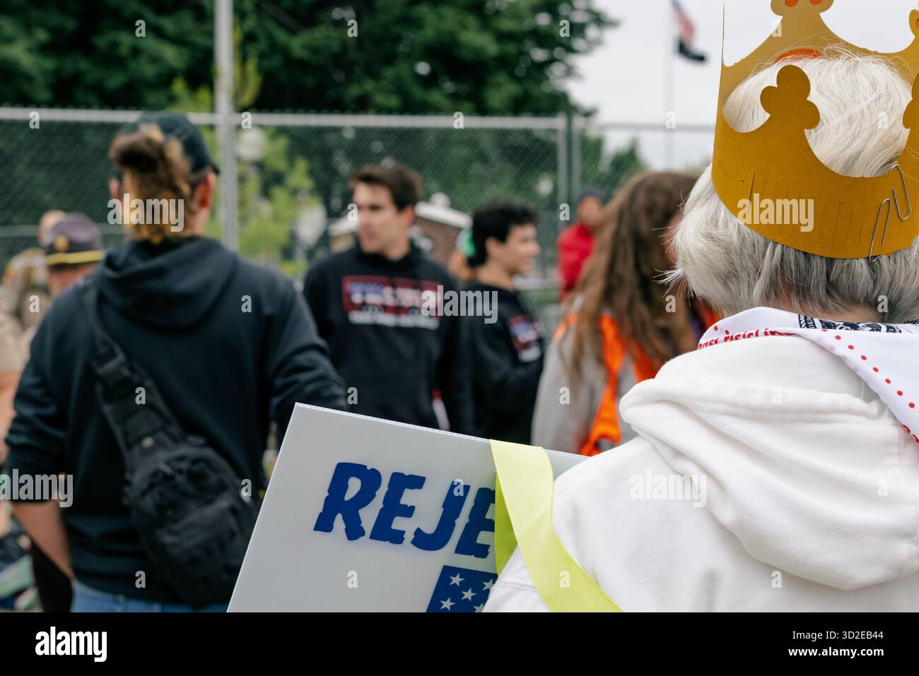 Ältere Demonstrantin in goldener Krone hält politisches Zeichen vor Trump-Anhängern bei der Demonstration „No Kings Day“ am 14. Juni 2025 in St. Paul, USA Stockfoto