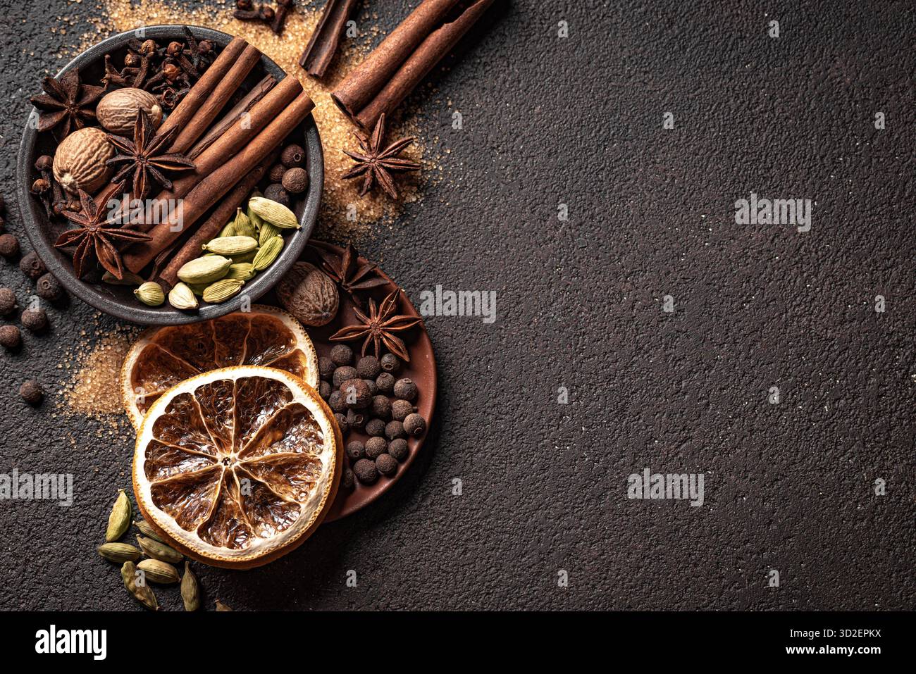 Traditionelle weihnachtliche aromatische Gewürze, trockene Orangen und brauner Zucker, Blick von oben, Kopierraum. Zutaten für Glühwein oder Backen. Ästhetische weihnachtliche Duftschablone. Stockfoto