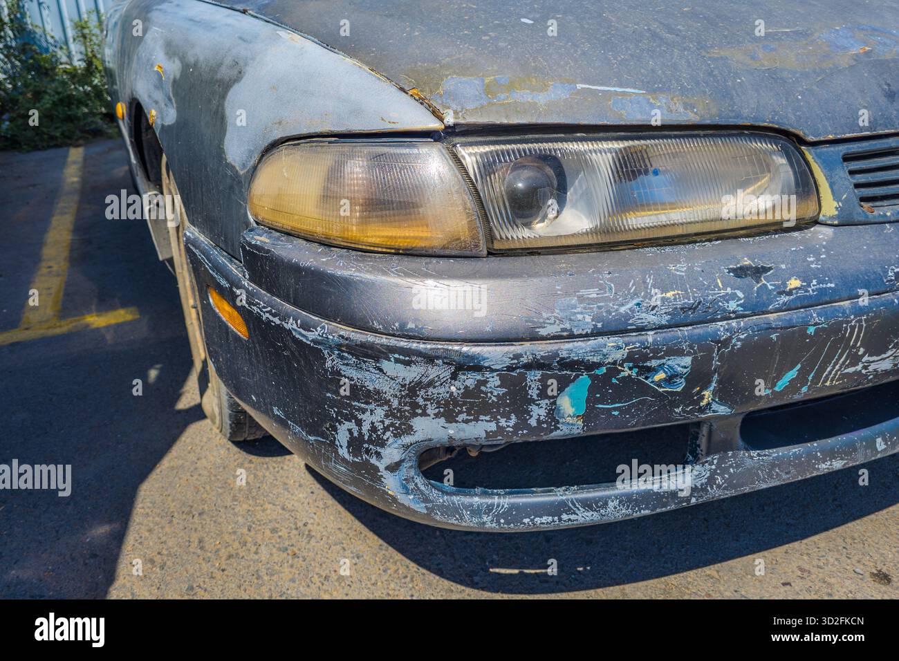 Das alte Auto zeigt tagsüber Abnutzungen auf dem Parkplatz Stockfoto