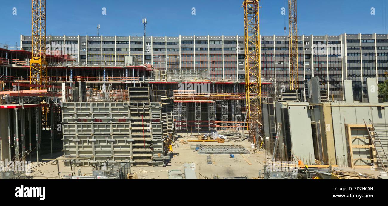 Berlin, Deutschland - 13. Mai 2025: Baustelle mit Kränen, Baumaterialien und laufenden Arbeiten unter klarem blauem Himmel. - Smartphone-aufgenommenes Stockfoto
