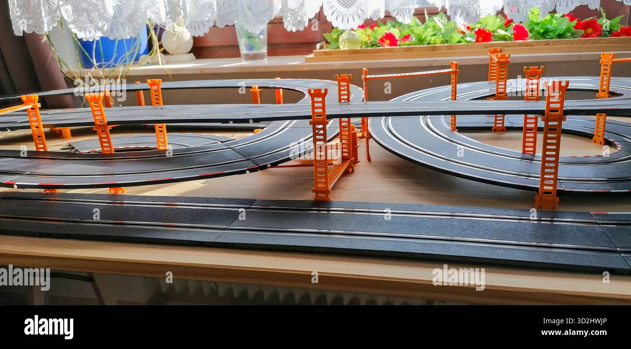 Teilansicht einer privaten Spielautomobilbahn mit erhöhten Brückenabschnitten, die eine dynamische Miniatur-Rennszene schaffen. Stockfoto