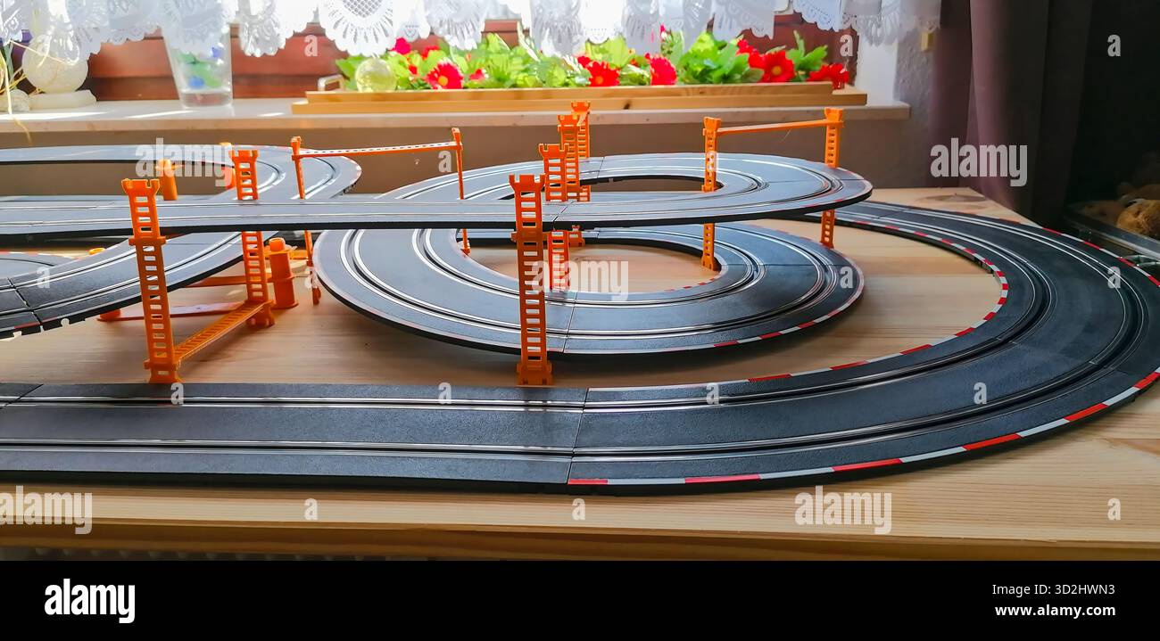 Teilansicht einer privaten Spielautomobilbahn mit erhöhten Brückenabschnitten, die eine dynamische Miniatur-Rennszene schaffen. Stockfoto