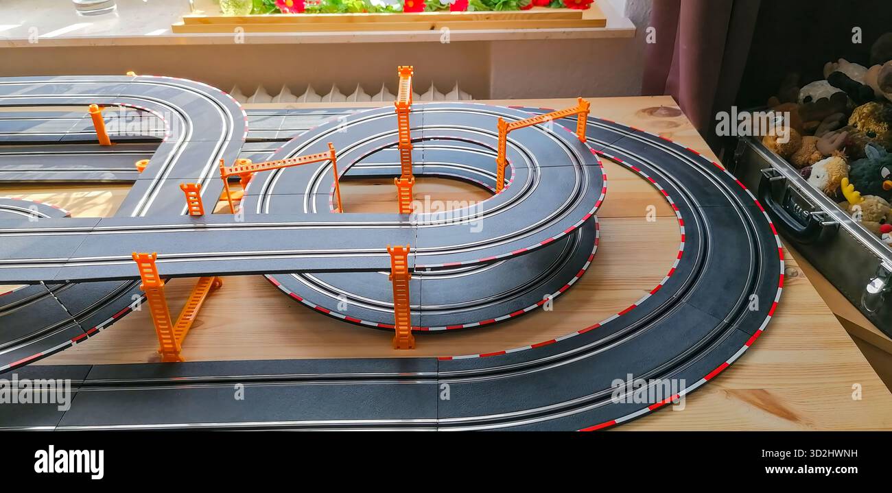 Teilansicht einer privaten Spielautomobilbahn mit erhöhten Brückenabschnitten, die eine dynamische Miniatur-Rennszene schaffen. Stockfoto