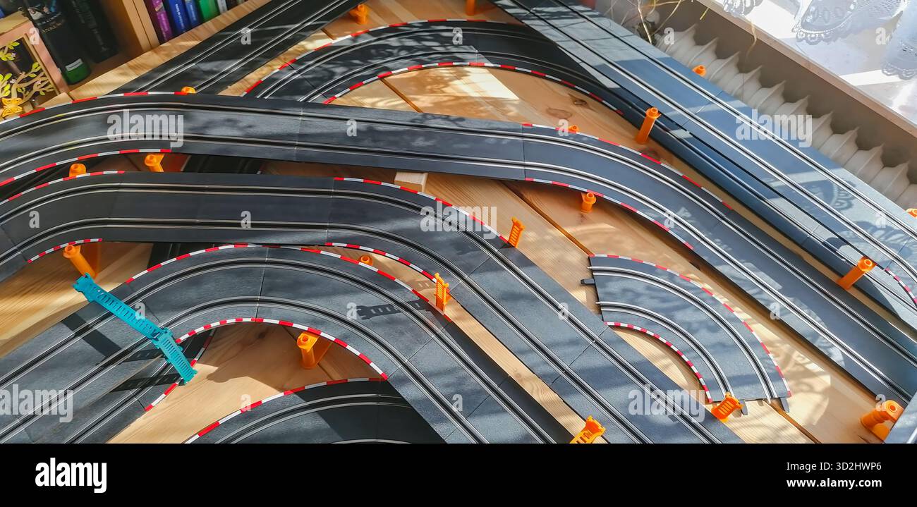 Teilansicht einer privaten Spielautomobilbahn mit erhöhten Brückenabschnitten, die eine dynamische Miniatur-Rennszene schaffen. Stockfoto