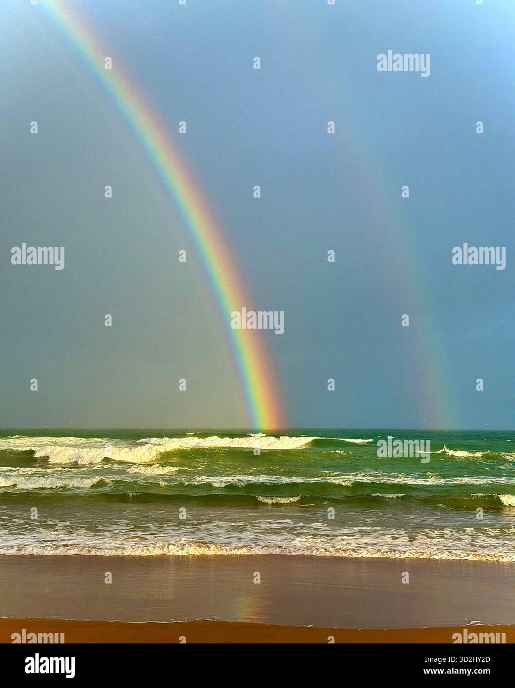 Doppelter Regenbogen über Ozeanwellen an einem tropischen Strand nach Regenfällen, Salvador, Bahia, Brasilien. - Smartphone-aufgenommenes Stockfoto