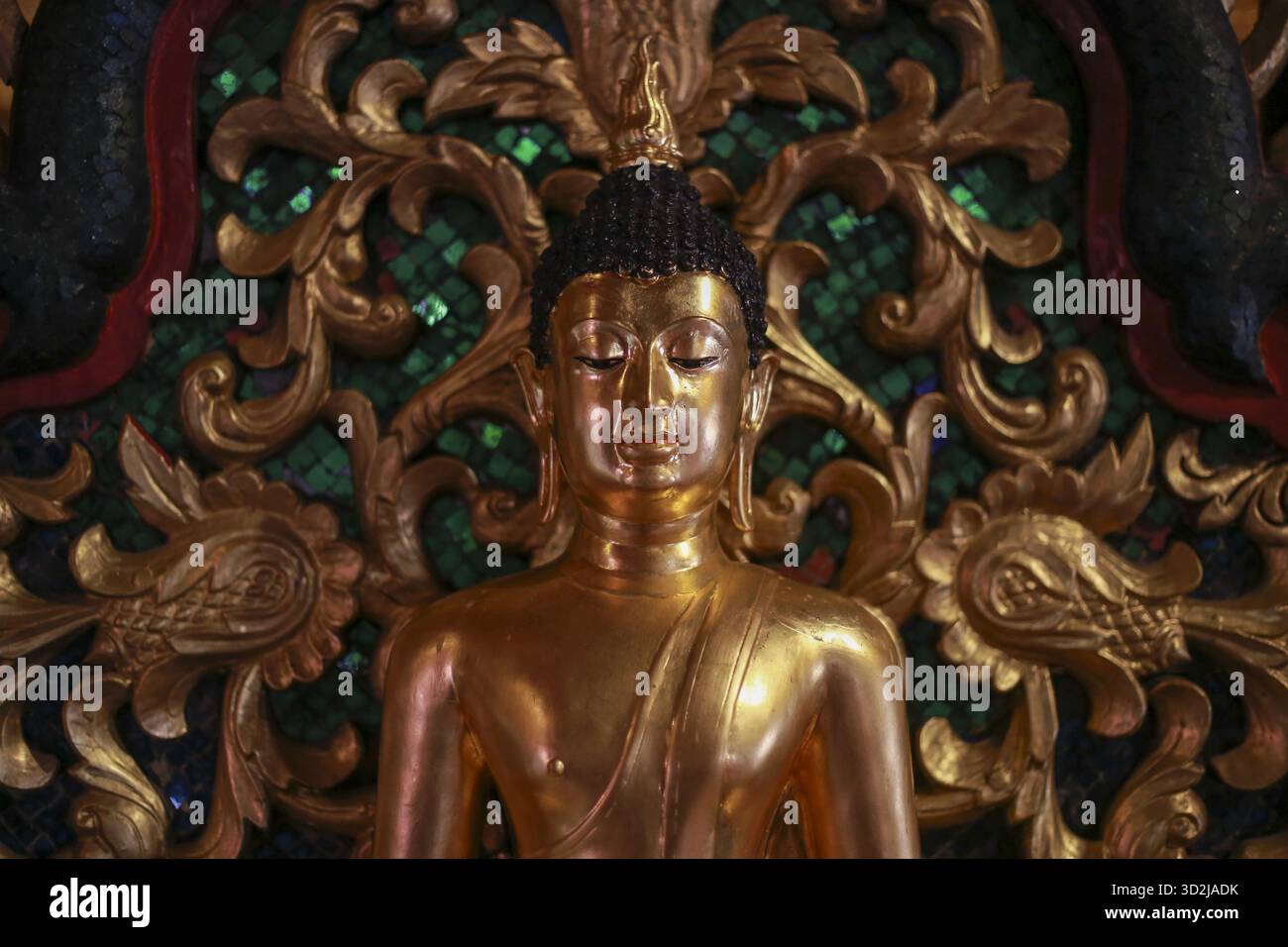 Die goldene buddha-Statue strahlt eine ruhige und friedliche Aura aus und symbolisiert Meditation und spirituelle Erleuchtung. Kunstvolle Schnitzerei schafft eine komplizierte Backgr Stockfoto