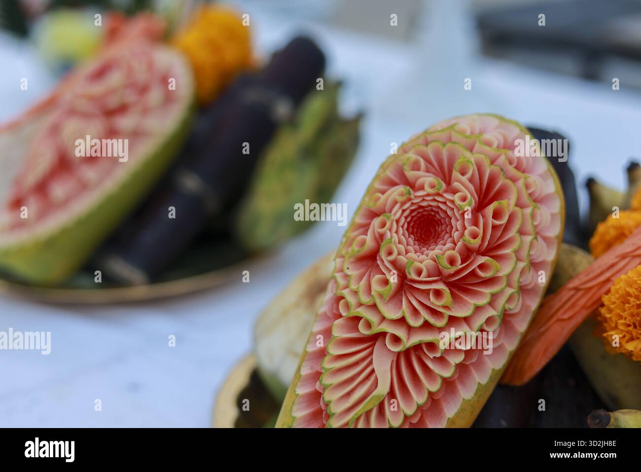 Komplizierte Obstschnitzerkunst mit detaillierter Essensskulptur aus roter Wassermelone. Dieses wunderschöne und traditionelle thailändische Kunsthandwerk schafft ein beeindruckendes Zentrum Stockfoto