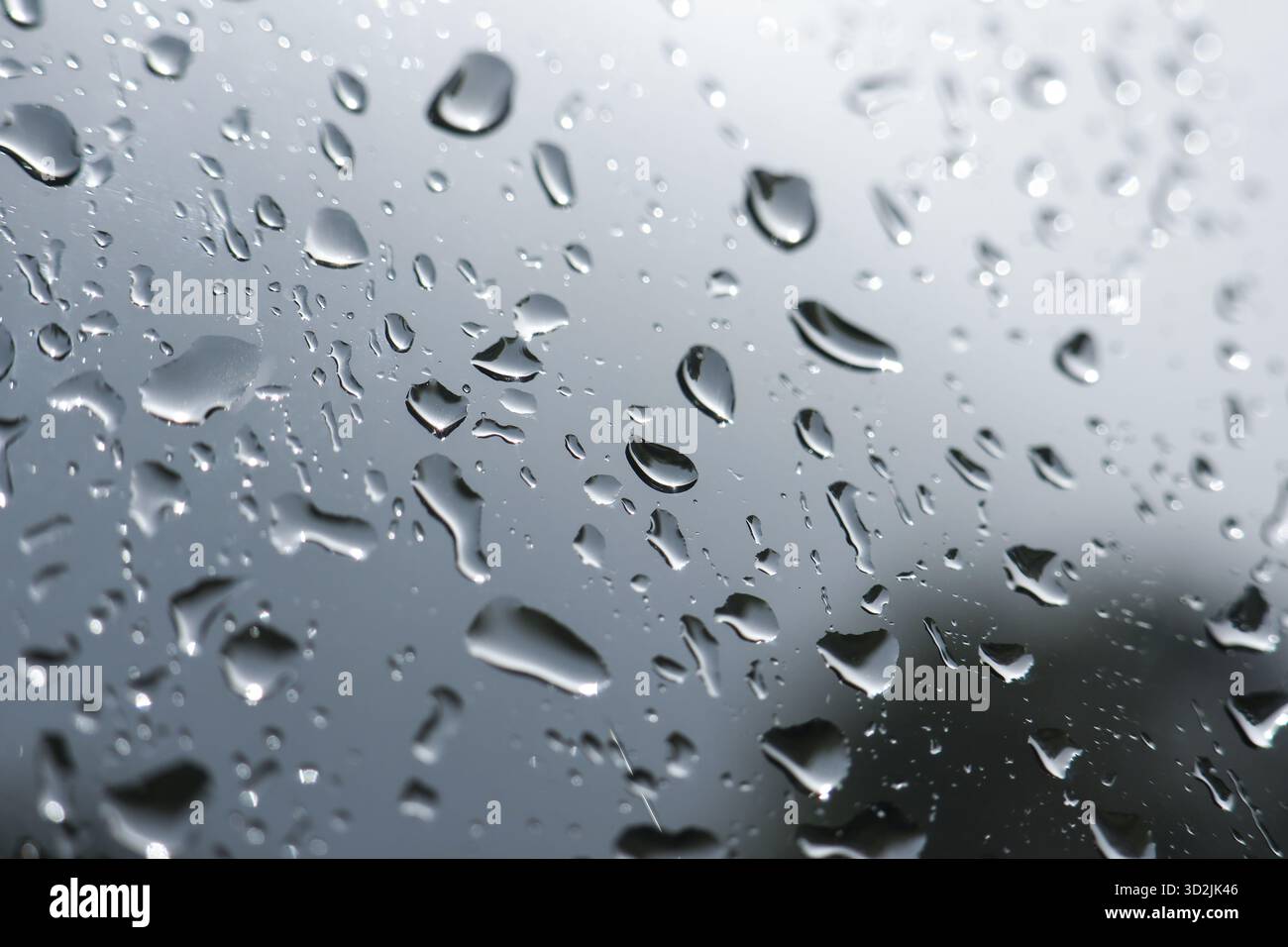 Melancholischer Blick auf Regentropfen und reines Wasser auf nassem Fenster. Graues, düsteres Wetter erzeugt einen abstrakten Hintergrund mit Kondensation auf transparentem Hintergrund Stockfoto