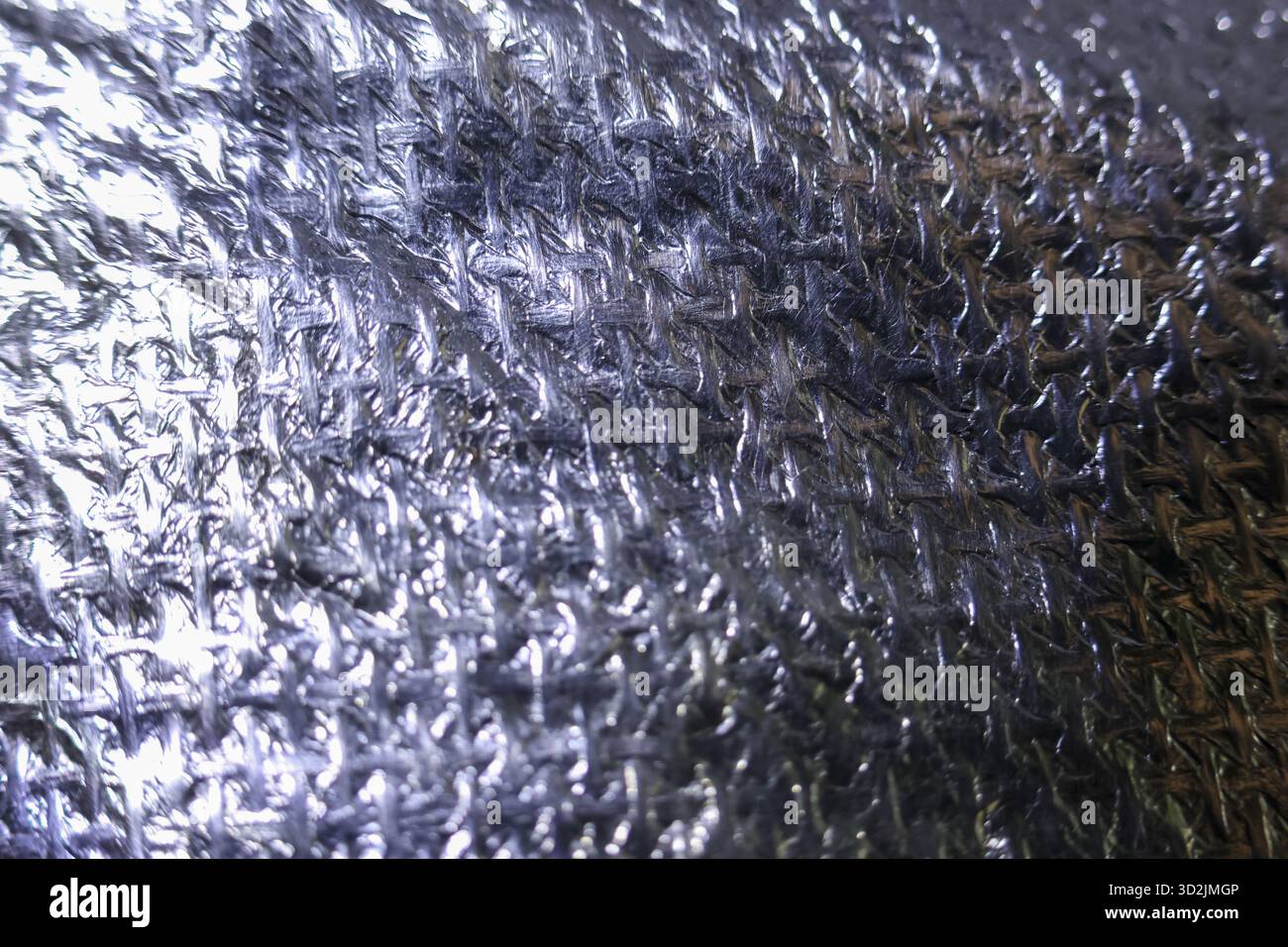 Glänzende Silberfolie Hintergrund mit zerknitterter, metallischer Textur. Eine abstrakte, reflektierende Oberfläche, Nahaufnahme des Isoliermaterials, das holprig und ungeschliffen zeigt Stockfoto