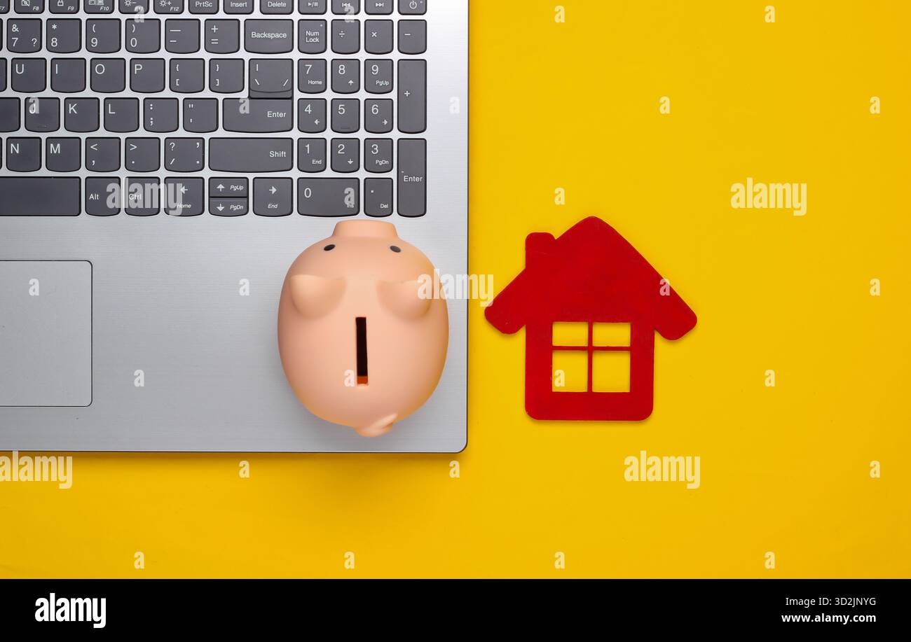 Sparen Sie für das Wohnen. Laptop, Schweinebank mit Hausfigur auf gelbem Hintergrund. Draufsicht Stockfoto