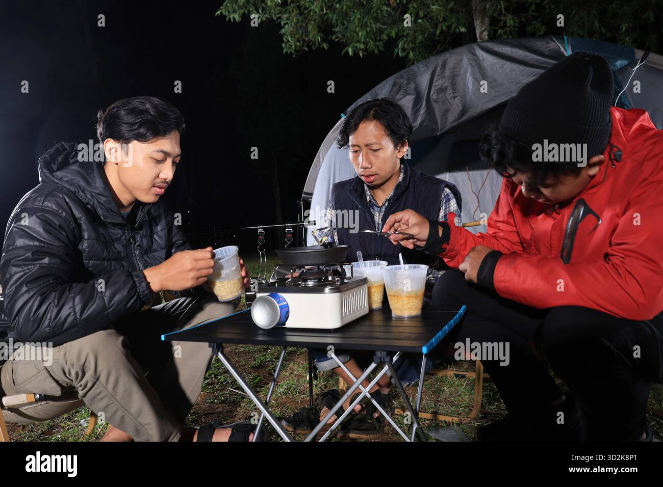 Gruppe junger asiatischer Mann kocht sofort Noodel Cup vor dem Campingzelt Stockfoto