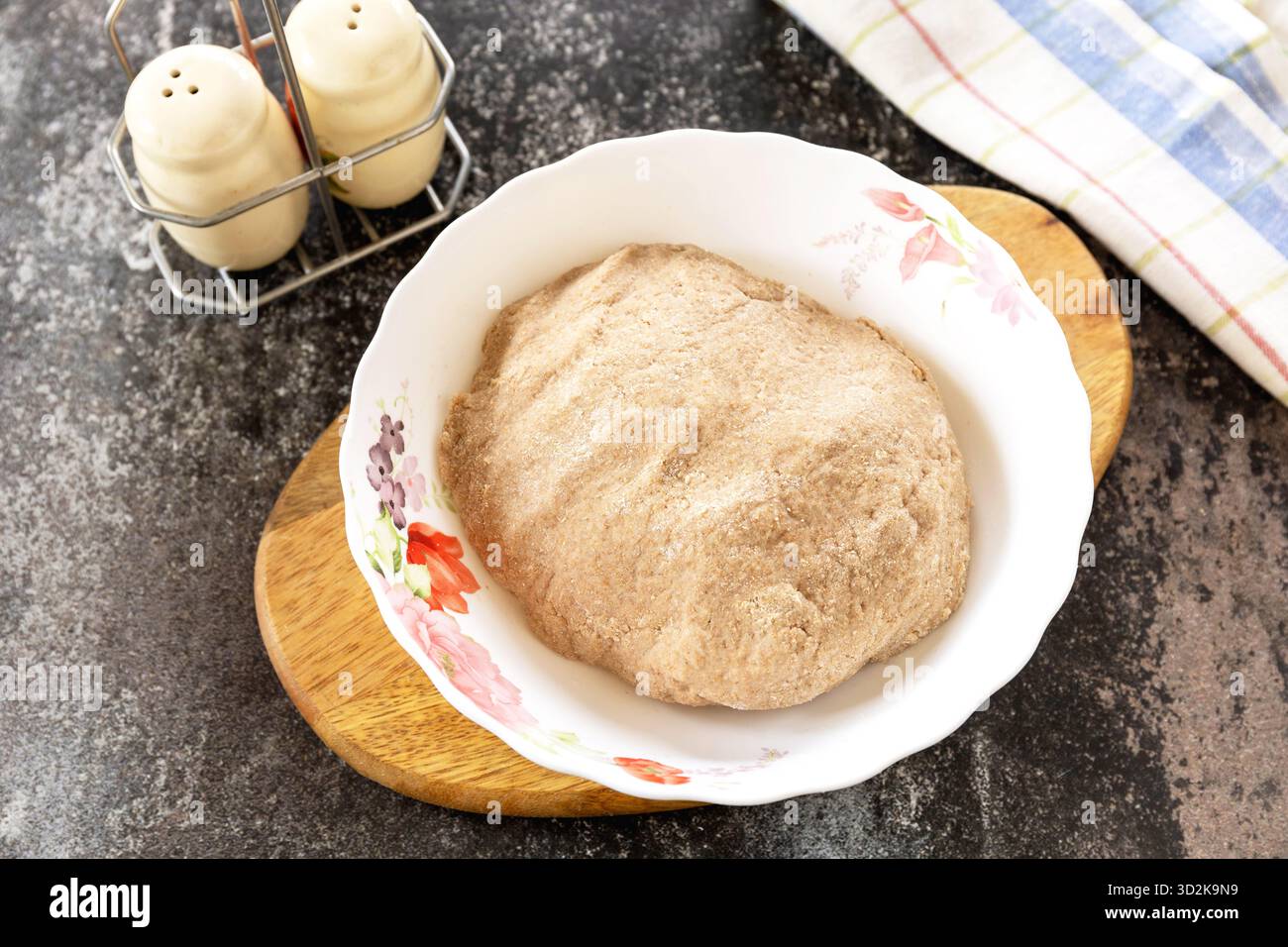 Hausgemachte Teigzubereitung auf Holzbrett mit Salz- und Pfefferstreuern, bereit für das traditionelle Backen. Ster 2. Stockfoto