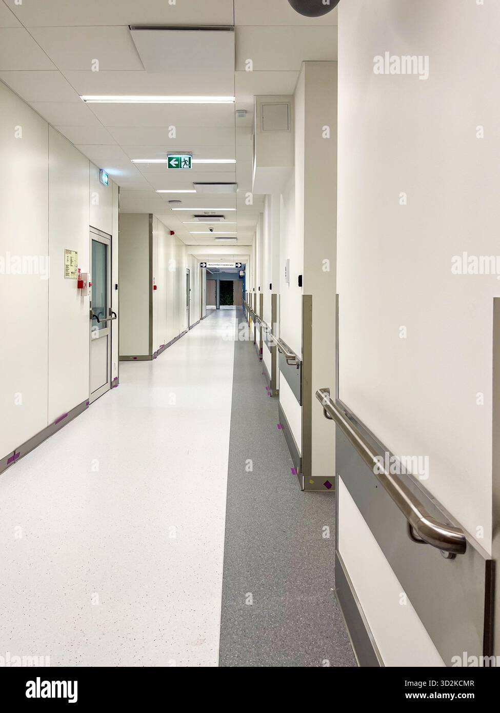 Der hell beleuchtete Krankenhausflur besticht durch ein modernes Design mit Sicherheitsgeländern, die eine saubere und einladende Umgebung für die Gesundheitsfürsorge und die Pflege betonen Stockfoto